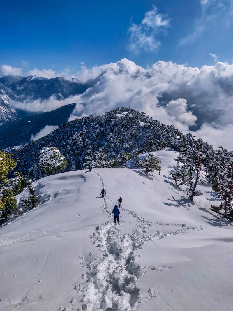 Trekkers crossing a snow-covered Himalayan ridge
