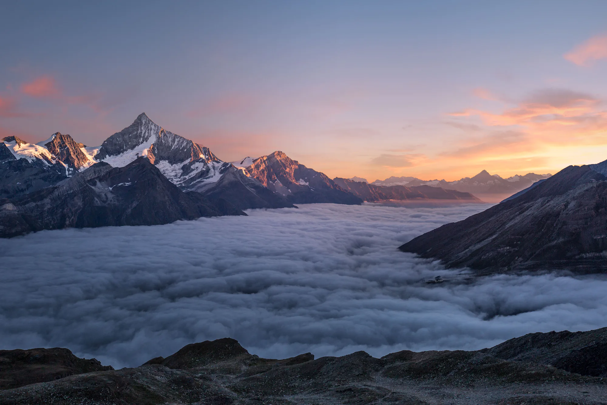 Snow-capped peaks rising above a sea of cloud at sunrise