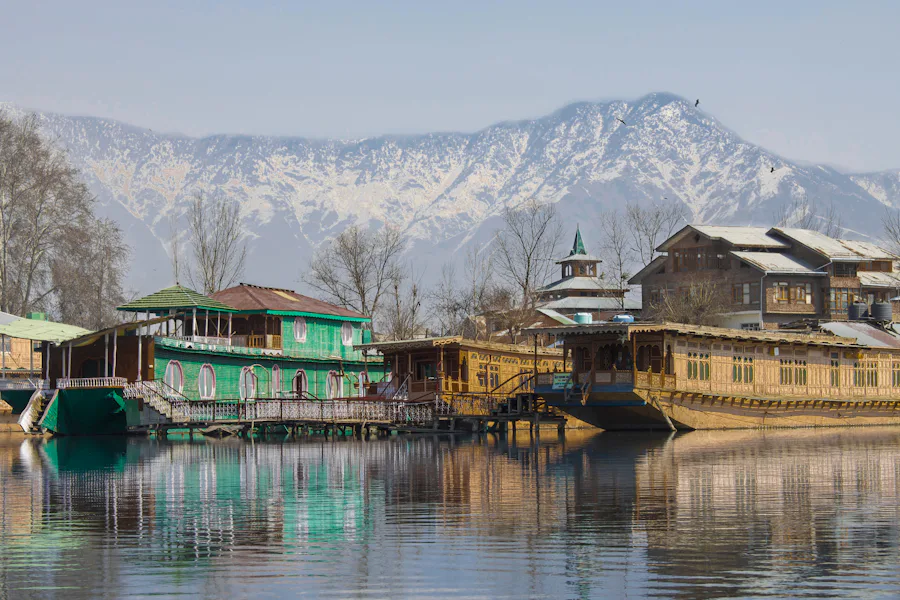 Wooden houseboats on Dal Lake with snow-covered mountains behind