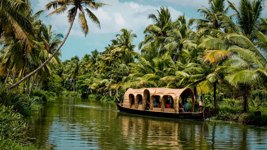 A traditional houseboat moving through palm-lined Kerala backwaters
